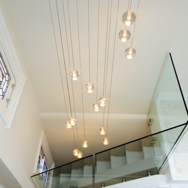 Modern staircase with glass railing and pendant lights hanging from the ceiling.