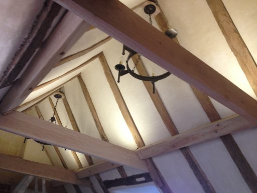 Ceiling view with wooden beams and hanging lights in a rustic setting.