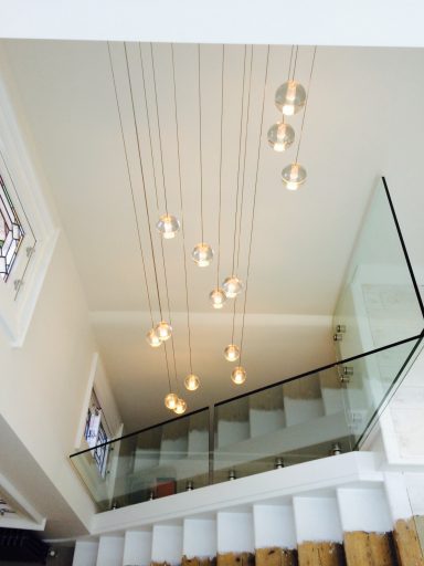 Modern staircase with a glass railing and pendant lights hanging from the ceiling.