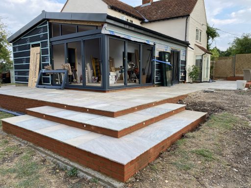 A modern home extension with steps leading up to a glass-walled living space.