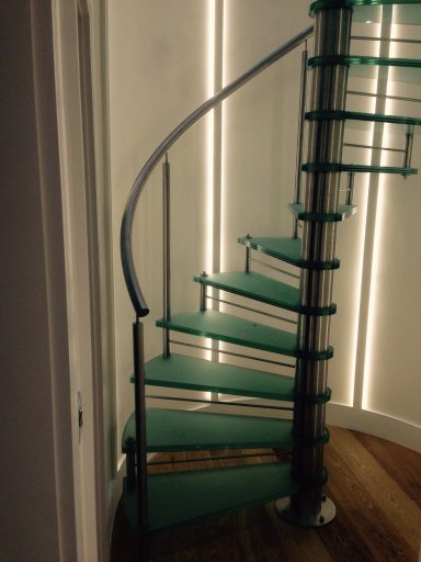 A modern spiral staircase with glass steps and ambient lighting.