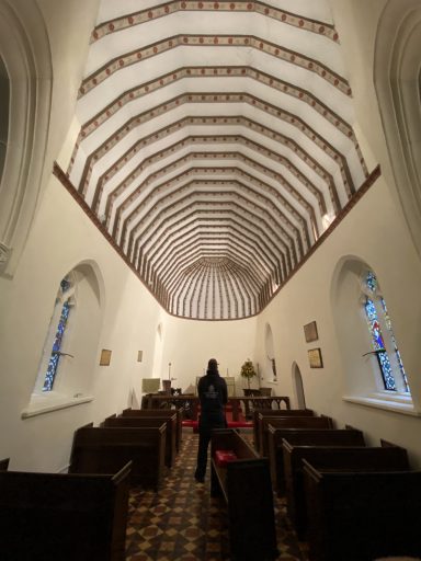 Interior of a church featuring a high, vaulted ceiling and wooden pews.