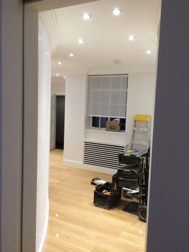 Interior view of a partially finished room with wooden flooring and tools visible.