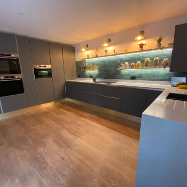 Modern kitchen with grey cabinetry, sleek countertops, and ambient lighting.