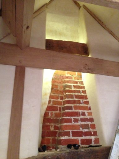 Exposed red brick chimney within a wooden-beamed roof structure.