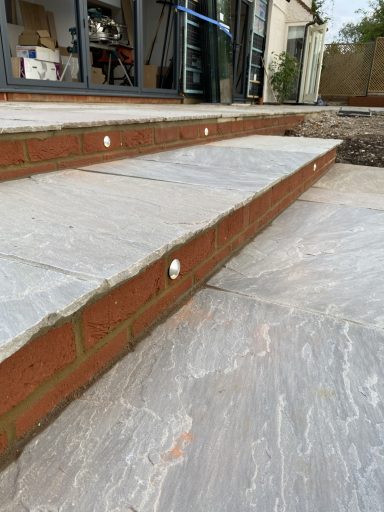 Stone steps with brick edges lead to a doorway, featuring ground-level textures.