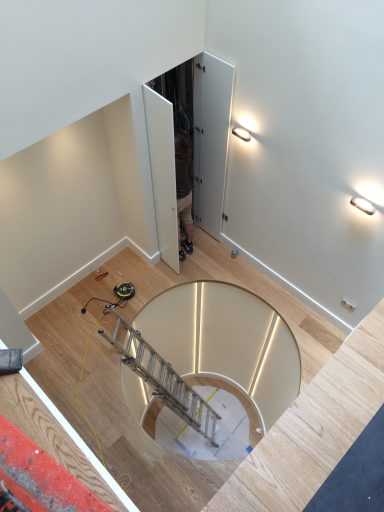 A circular opening in the floor, with a ladder and construction tools nearby.