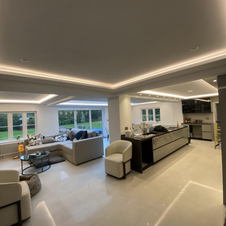 Modern open-plan kitchen and living area with grey furniture and ample natural light.