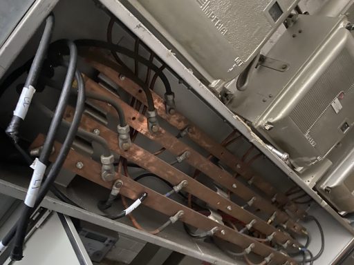 Exposed electrical wiring and copper busbars inside a metal cabinet.