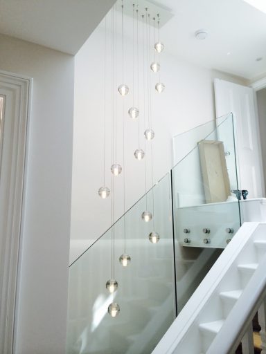 Modern pendant lights hanging from a ceiling, illuminating a staircase area.