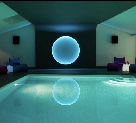 Indoor swimming pool with ambient lighting and brightly coloured seating.