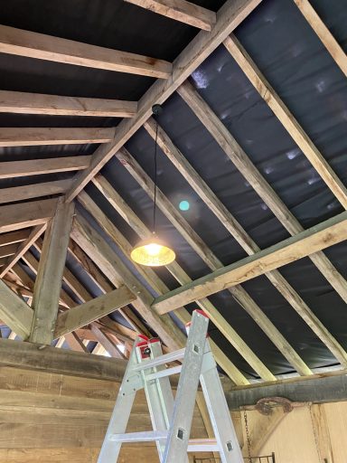 Interior of a building under construction, showing exposed beams and a light fixture.