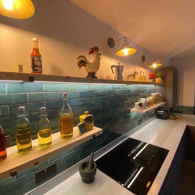 Bottles of sauces and oils on shelves above a kitchen countertop and a decorative rooster.