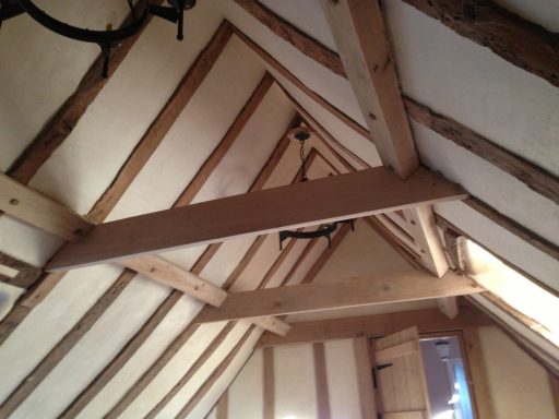 Interior view of a room with exposed wooden beams and sloped ceiling.