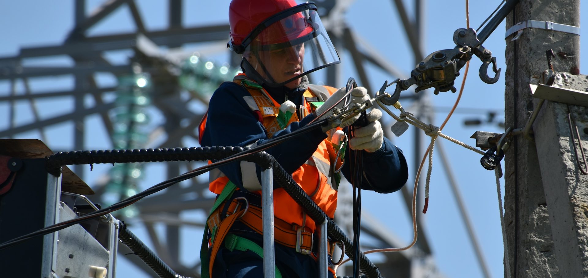 Worker in safety gear performing maintenance on telephone lines.