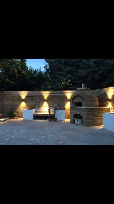 Outdoor area featuring a stone pizza oven, seating, and ambient lighting.