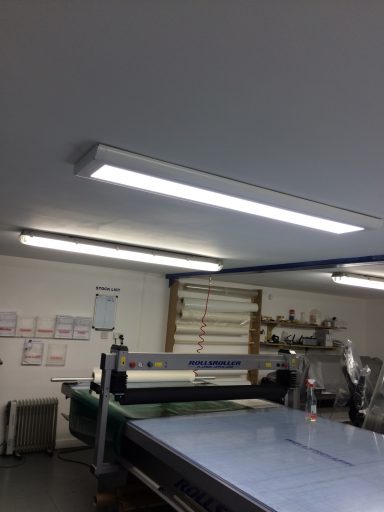 Brightly lit ceiling of a workshop with worktables and tools in the background.