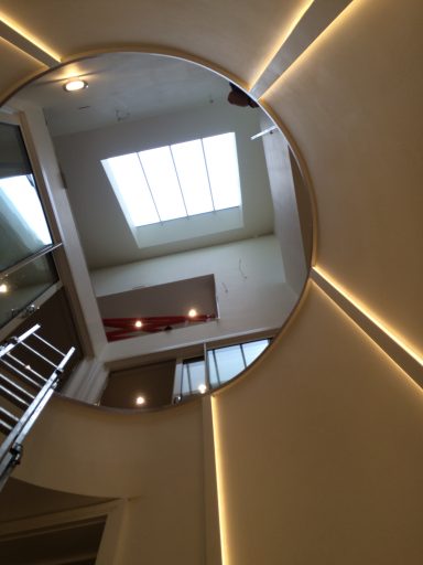 Circular view of a staircase with modern lighting and a skylight above.