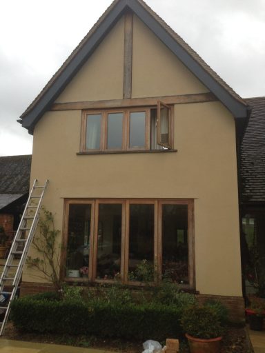 Two-storey house with wooden features and a ladder leaning against it.