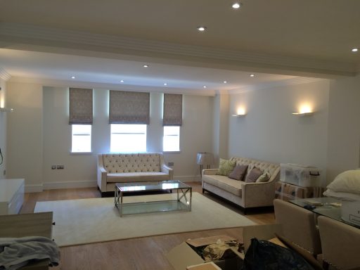Bright, modern living room with beige sofas, a glass coffee table, and large windows.