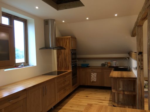 Modern kitchen with wooden cabinetry, stainless steel appliances, and wooden flooring.