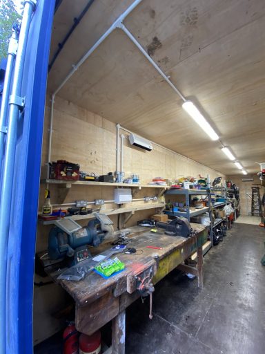 Interior of a workshop with tools and equipment on shelves and a workbench.