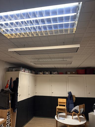 Interior of a room with ceiling lights, storage cabinets, and stacked chairs.