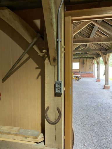 A horseshoe hanging on a wooden wall in a rustic building interior.