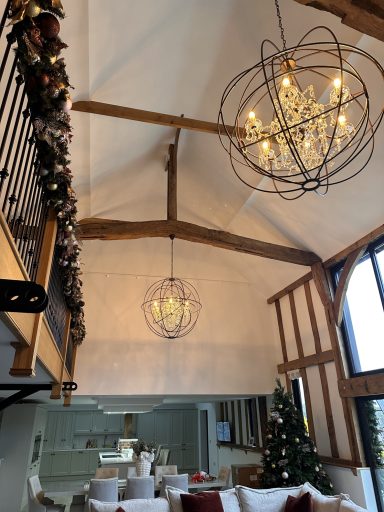 Stylish living space with high ceilings, modern chandeliers, and a Christmas tree.